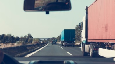 Car driving beside trucks